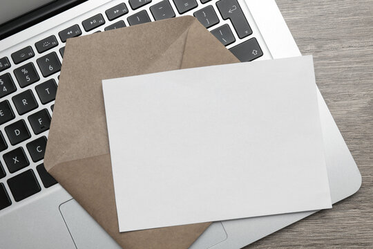 Brown Envelope With Blank Letter And Laptop On Wooden Table, Top View