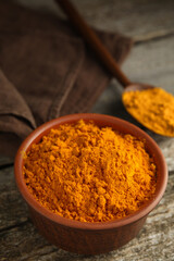 Bowl and spoon with saffron powder on wooden table