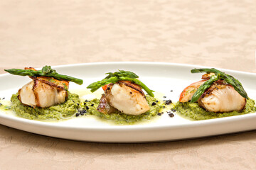 Mediterranean cuttlefish egg appetizer with asparagus on a white plate