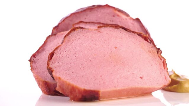 Fleischk&auml;se in Scheiben auf einem Drehteller freigestellt auf wei&szlig;em Hintergrund