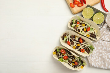 Fototapeta na wymiar Delicious tacos with fried meat, vegetables and cheese on white wooden table, flat lay. Space for text