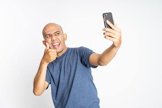 Happy asian bald man showing thumbs up when selfie on isolated background