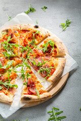 Close up of  sliced ​​pizza with meat jamon and arugula