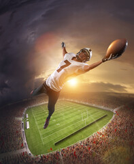 Fototapeta na wymiar American football players catching ball in flight overt stadium with flashlights at evening time. Concept of sport, movement, achievements, leadership.