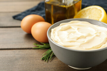 Bowl with fresh mayonnaise and ingredients on wooden table, closeup. Space for text