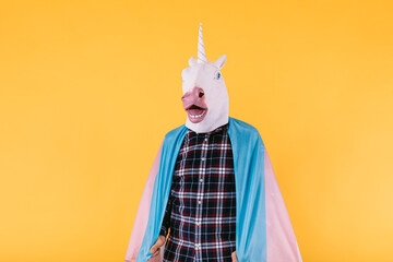 Person dressed in a unicorn mask with a checkered shirt holding the flag of the transsexual...