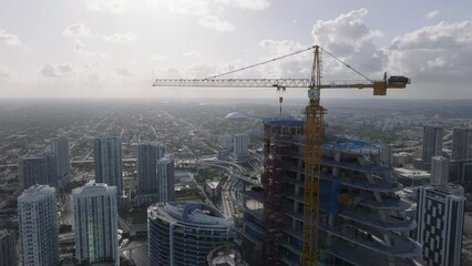 alt flying counter clockwise around construction crane atop skyscraper in Miami - Powered by Adobe