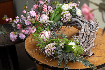 Beautiful hand made spring wreath made of branches, green leaves, eucalyptus and flowers on rustic wooden background. Spring wreath for door, vintage style decor.