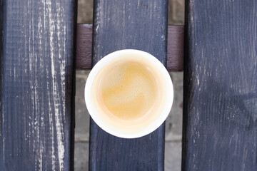 Paper cup with coffee on a wooden bench