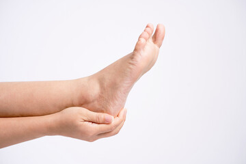 Woman holding her painful heel on white background.