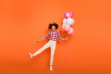 Full length body size view of attractive cheerful girl jumping holding helium balls isolated on...