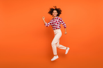 Fototapeta na wymiar Full length body size view of attractive cheery sporty girl jumping running isolated on bright orange color background