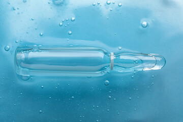 Pharmaceutical ampoule with medication in transparent gel on light blue background, closeup