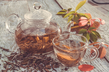 Glass teapot and cup with green tea on old wooden table.