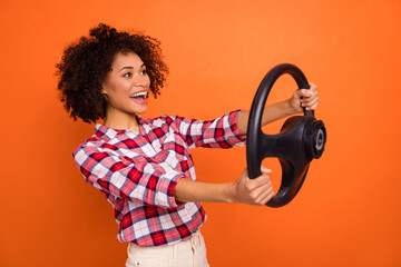 Profile side view portrait of attractive trendy cheerful girl holding steering wheel having fun isolated over bright orange color background