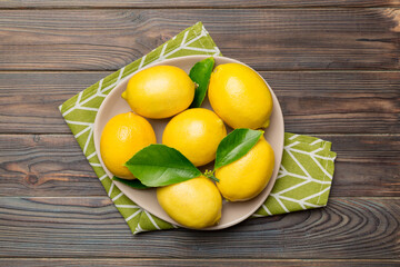 Fresh cutted lemon and whole lemons over round plate on colored background. Food and drink ingredients preparing. healthy eating theme top view vith copy space