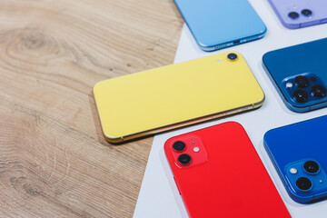 Arrangement with several multi-colored modern telephones. Mobile phones lie on the table with space...