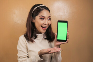 Naklejka premium Happy and smiling young Asian women showing a green blank screen.