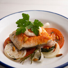 Baked hake with tomato and onion. Spanish traditional tapas.