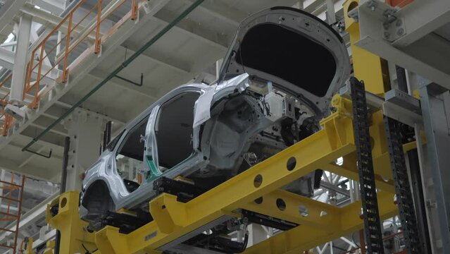 The car frame moves along the conveyor belt.