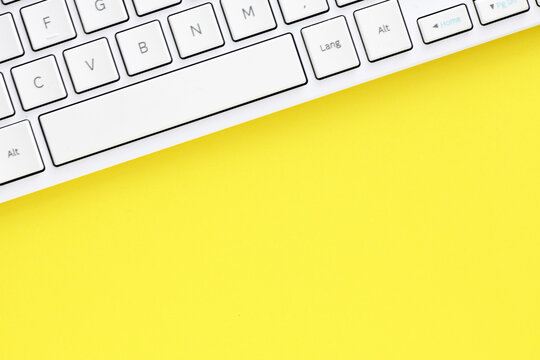 Close Up White Computer Keyboard On Yellow Background. View From Above.