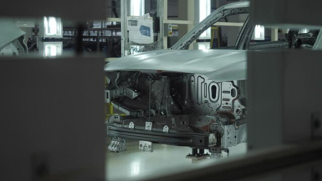 The car frame moves along the conveyor belt.