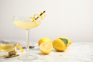 Delicious bee's knees cocktail and ingredients on white marble table. Space for text
