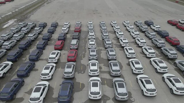 The new cars are lined up in the parking lot outside the production facility.