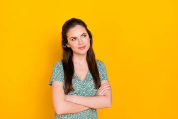 Photo of sweet dreamy woman wear print dress smiling arms folded looking empty space isolated yellow color background