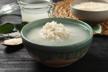 Bowl with rice soaked in water on wooden table