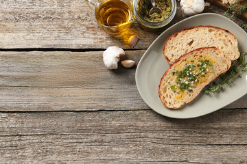 Tasty bruschettas with oil and garlic on wooden table, flat lay. Space for text