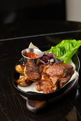 Grilled pork with baked golden potatoes served with red sauce on a dark background. Delicious Recipe. Pork Fillet Cooked