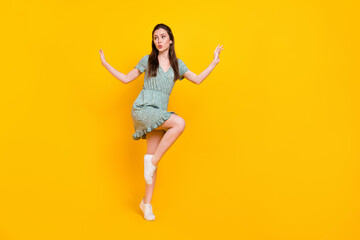 Fototapeta na wymiar Photo of excited impressed lady dressed green dress dancing looking empty space isolated yellow color background