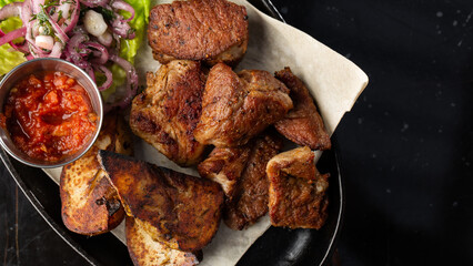 Grilled pork with baked golden potatoes served with red sauce on a dark background. Delicious Recipe. Pork Fillet Cooked