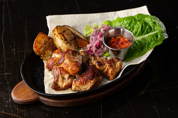 Grilled pork with baked golden potatoes served with red sauce on a dark background. Delicious Recipe. Pork Fillet Cooked