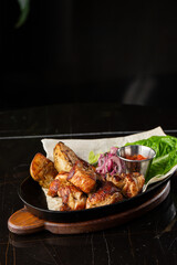 Grilled pork with baked golden potatoes served with red sauce on a dark background. Delicious Recipe. Pork Fillet Cooked