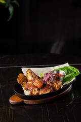 Grilled pork with baked golden potatoes served with red sauce on a dark background. Delicious Recipe. Pork Fillet Cooked