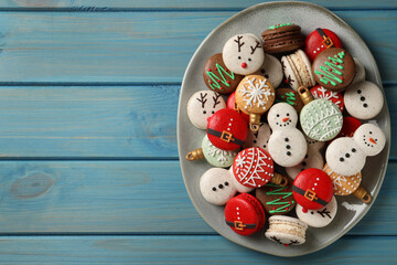 Beautifully decorated Christmas macarons on light blue wooden table, top view. Space for text