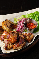 Grilled pork with baked golden potatoes served with red sauce on a dark background. Delicious Recipe. Pork Fillet Cooked