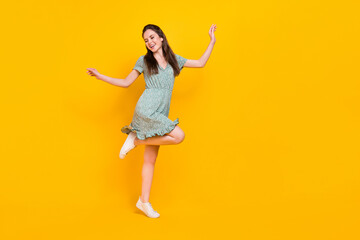 Photo of cute excited lady dressed green dress dancing empty space isolated yellow color background