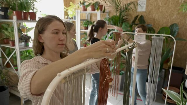 Group of women attending art class. Female students and teacher makes home decor in Boho style in workshop together. Weaves handmade macrame at art school studio. Creativity, people education