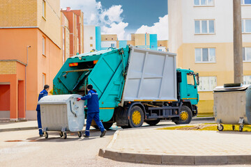 An automobile garbage truck collects garbage in residential areas of a modern city. Men load a...