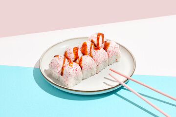 Maki roll with crab on coloured background. Sushi roll with crab, cheese and tobiko caviar topped. Maki sushi in minimal style. Japanese menu concept.