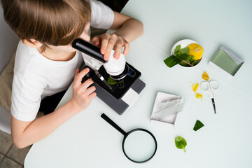 A little boy studies plants in a microscope, back to school, schoolboy, ecology, earth day