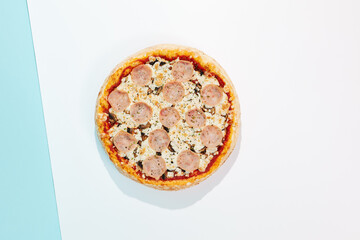 Italian pizza with ham and mushrooms on coloured background. Ham pizza in minimal style on orange and blue colours. American pizza delivery concept with color backdrop