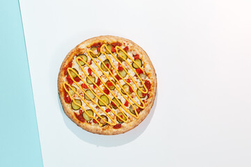 Italian pizza with chicken and pickled cucumber on coloured background. Cheese pizza with chicken in minimal style on purple and blue colours. American pizza delivery concept with color backdrop