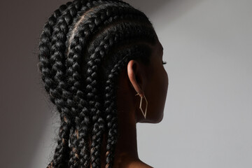 Close-up of African young woman with long braids posing on white background. - obrazy, fototapety, plakaty