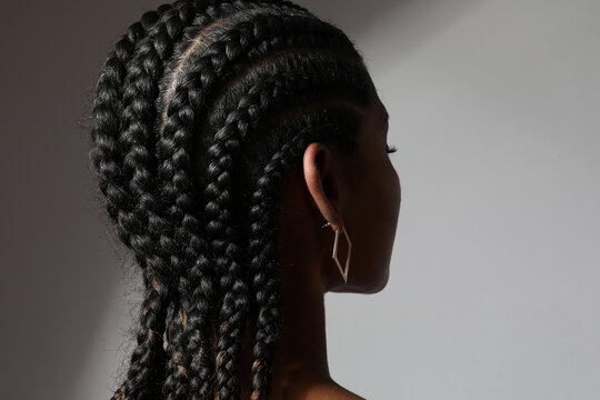 Close-up of African young woman with long braids posing on white background.