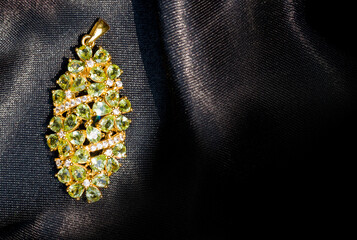 Peridot and Diamond Jewel or gems pendant on black shiny polyester fabric background. Collection of...
