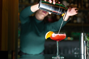 Fototapeta na wymiar Woman bartender serving a cocktail in a night club bar